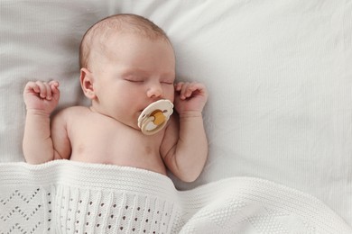 Photo of Adorable little baby with pacifier sleeping in bed, top view. Space for text