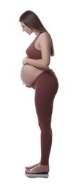 Photo of Pregnant woman standing on scales against white background