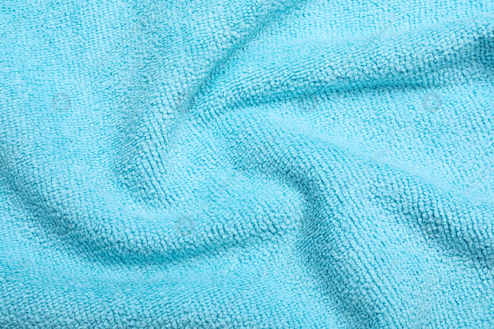 Photo of Crumpled light blue microfiber cloth as background, closeup