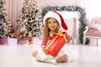 Photo of Cute little child with Christmas gift at home