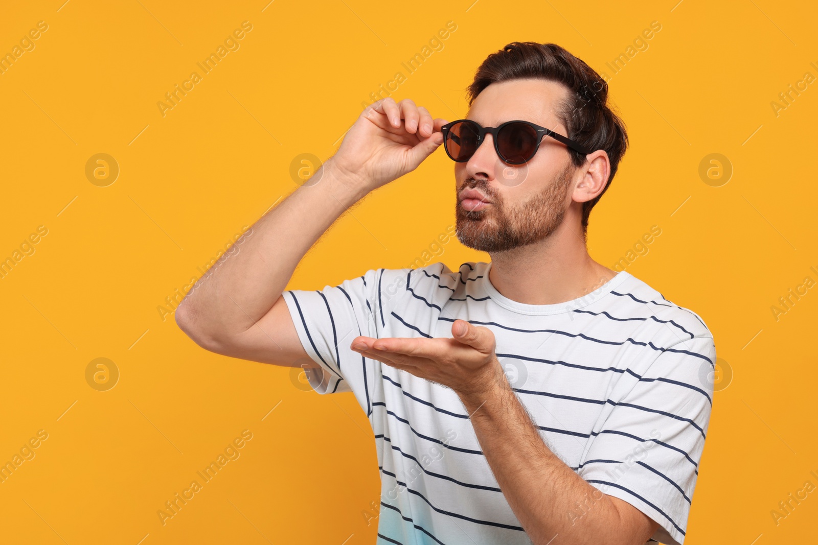 Photo of Handsome man blowing kiss on orange background