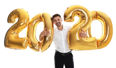 Happy young man with golden 2020 balloons on white background. New Year celebration