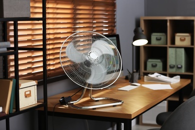 Photo of Modern electric fan on table in office