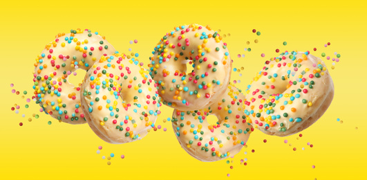 Image of Set of falling delicious donuts on yellow background. Banner design