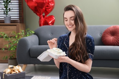 Photo of Beautiful young woman holding box with delicious cake in room. Happy Birthday
