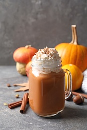 Photo of Mason jar with tasty pumpkin spice latte on gray table