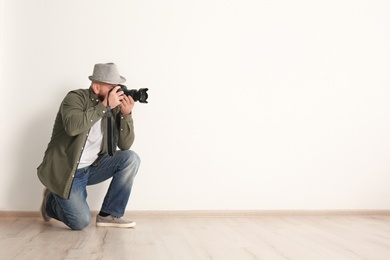Photo of Male photographer with camera near light wall