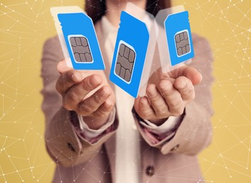 Image of Woman demonstrating SIM cards of different sizes on yellow background, closeup 