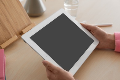 Photo of Woman using tablet at table, closeup. Space for design