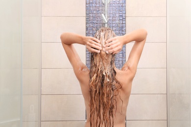 Young woman washing hair in shower at home