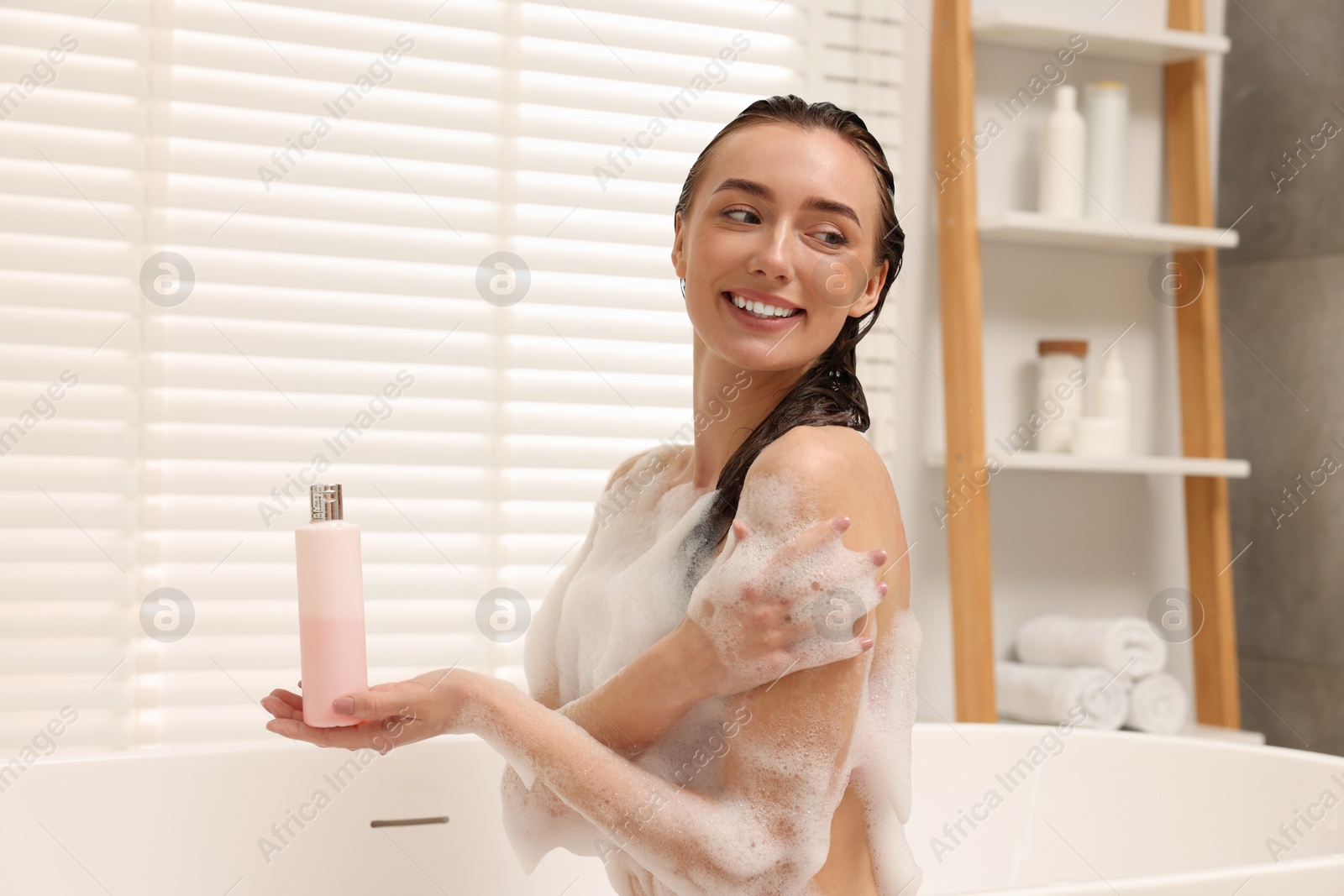 Photo of Woman taking bath with shower gel in bathroom