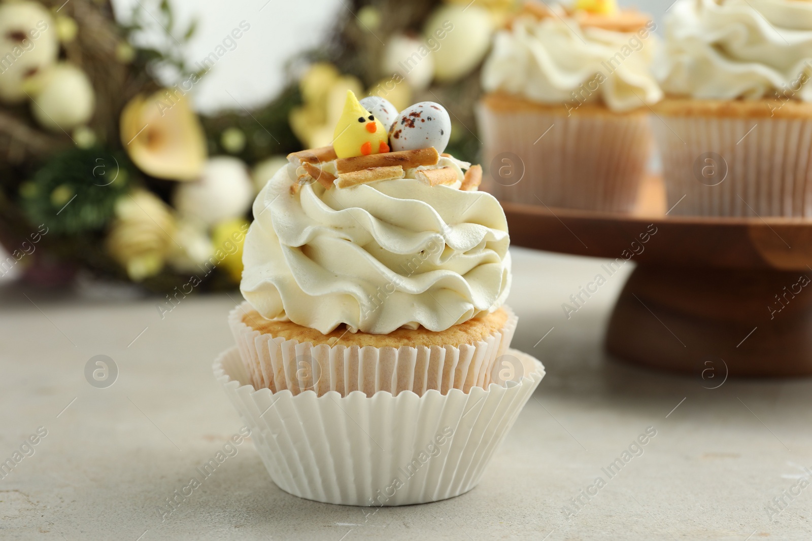 Photo of Tasty Easter cupcakes with vanilla cream on gray table