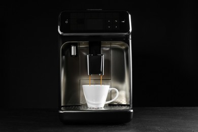 Making coffee with modern espresso machine on grey table against black background