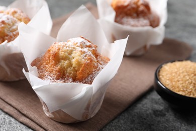Photo of Delicious muffins with powdered sugar on grey table, closeup