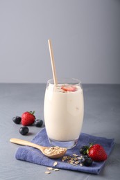 Tasty yogurt in glass, oats and berries on grey table