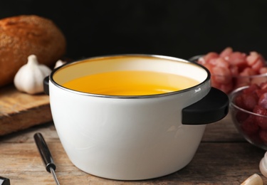 Pot with hot oil for meat fondue on table