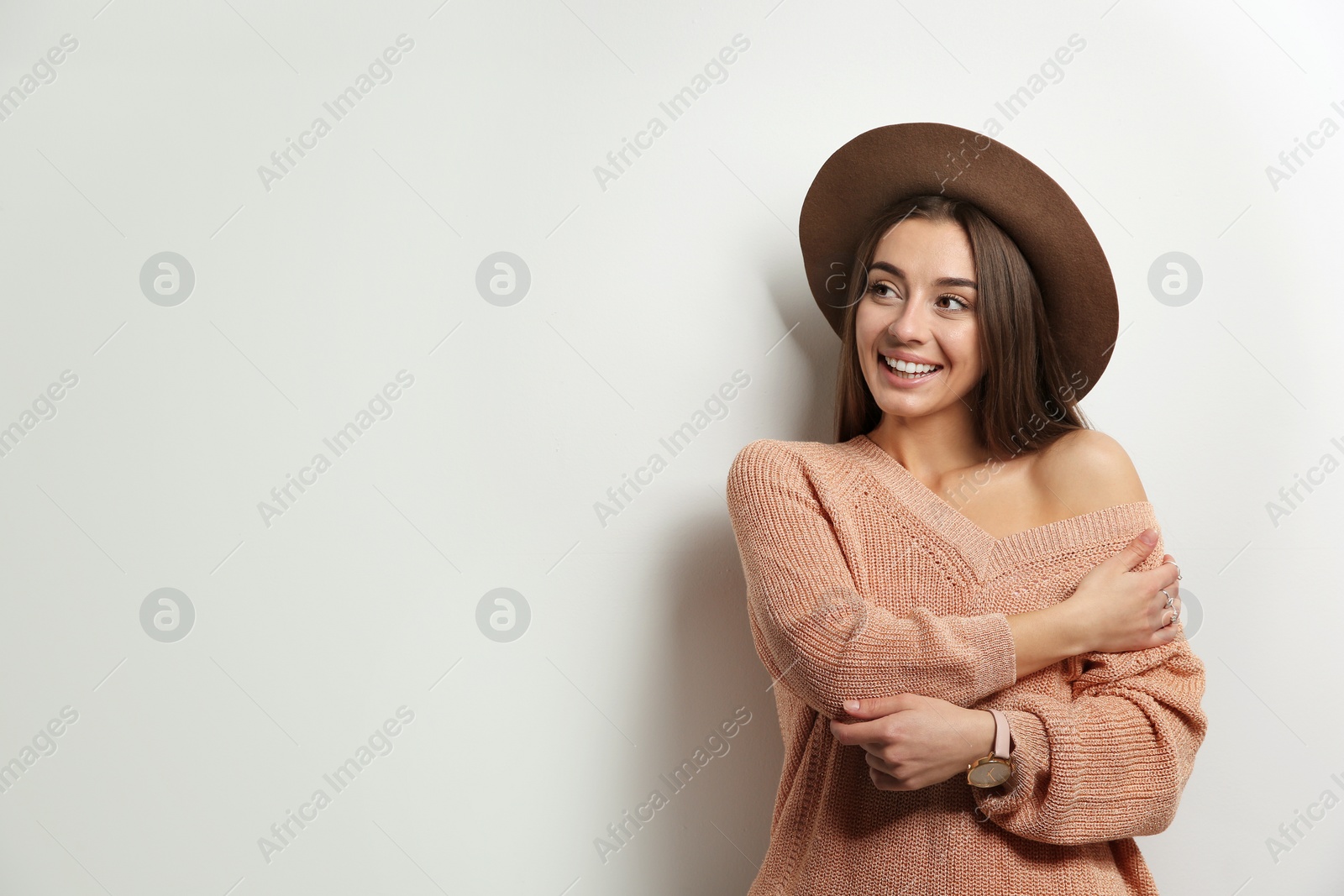 Photo of Beautiful young woman in warm sweater with hat on white background. Space for text