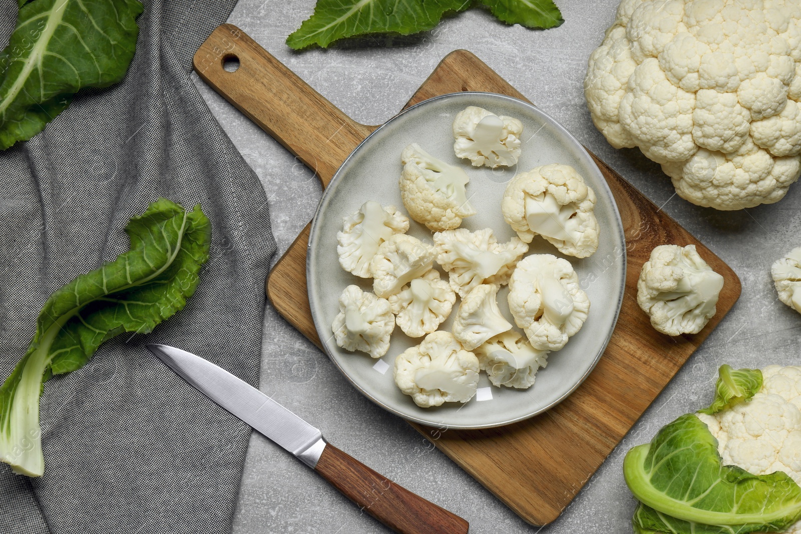 Photo of Cut and whole cauliflowers on grey table, flat lay