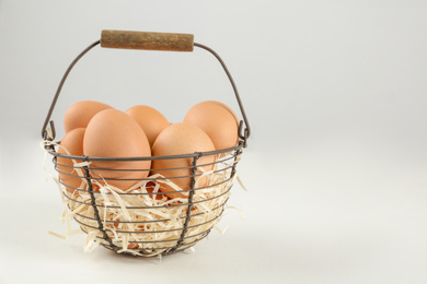 Raw chicken eggs and decorative straw on white table. Space for text