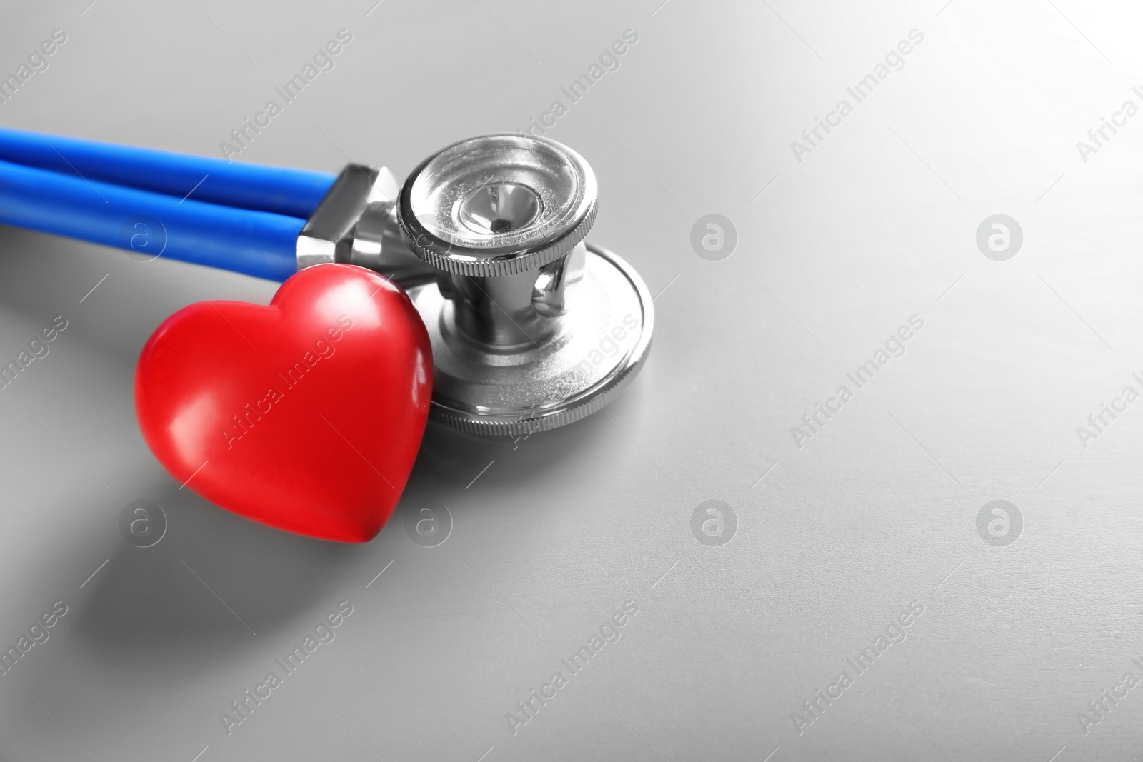 Photo of Stethoscope and small red heart on table. Heart attack concept