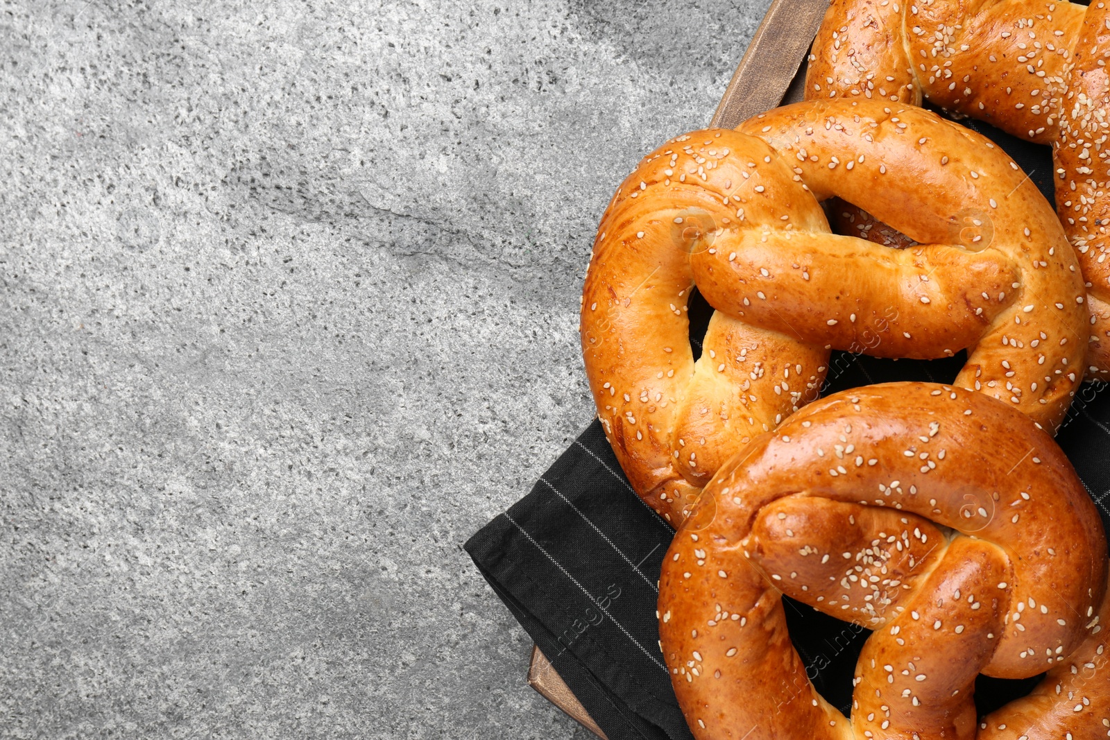 Photo of Delicious pretzels with sesame seeds on grey table, top view. Space for text