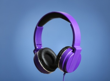 Stylish headphones with pads on color background