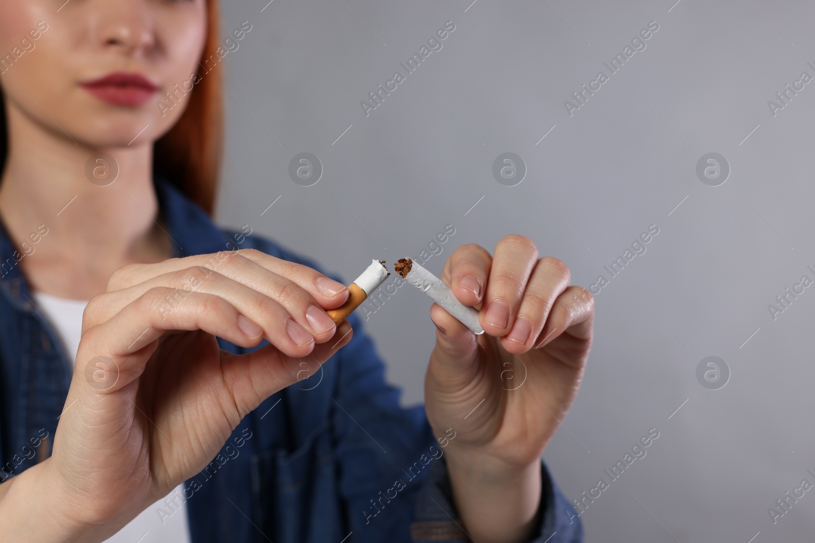 Photo of Stop smoking concept. Woman holding pieces of broken cigarette on light gray background, closeup with space for text