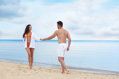 Photo of Happy young couple walking together on beach near sea