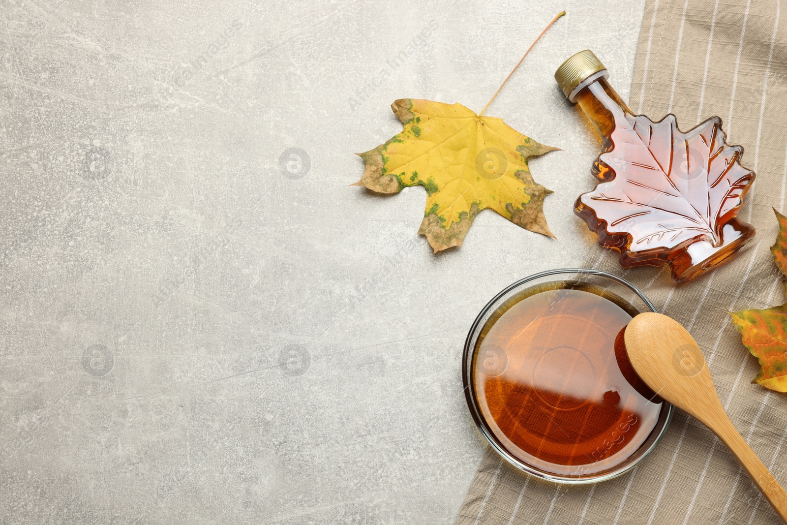 Photo of Flat lay composition with tasty maple syrup and dry leaves on light grey table, space for text