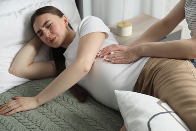 Doula taking care of pregnant woman in bedroom. Preparation for child birth