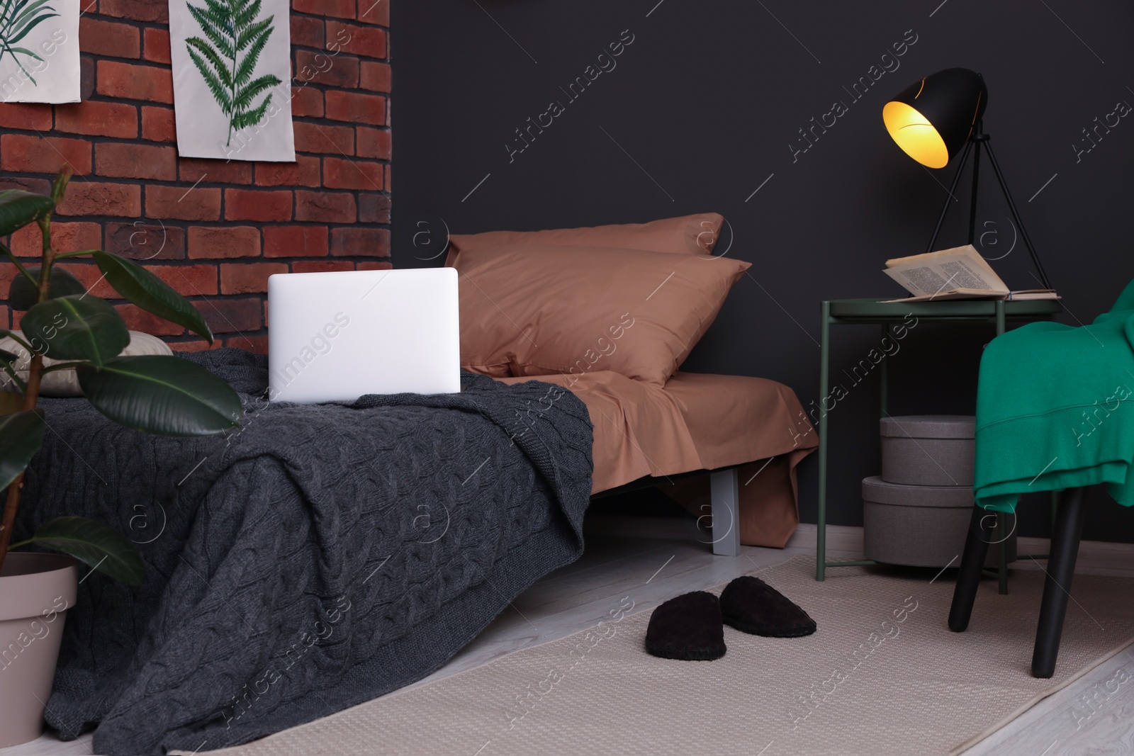 Photo of Stylish teenager's room with laptop on bed near brick wall