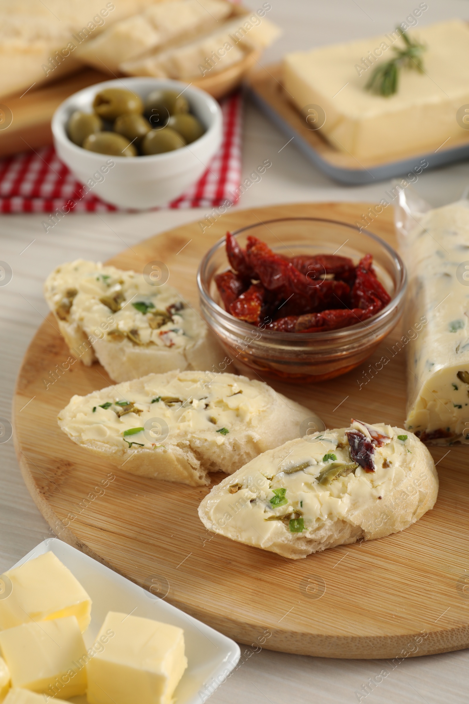 Photo of Tasty bread with butter, green onion, chili peppers and olives on wooden table