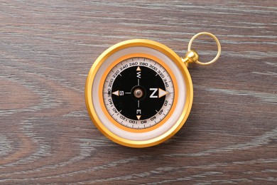 Photo of One compass on wooden table, top view