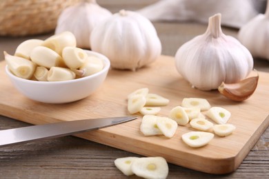 Aromatic cut garlic, cloves and bulbs on wooden table, closeup