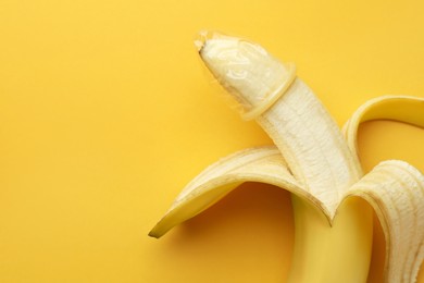 Photo of Banana with condom on orange background, top view and space for text. Safe sex concept