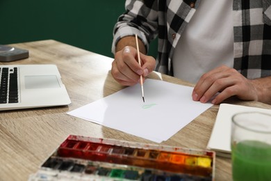 Photo of Man drawing with paints at table, closeup. Distance learning