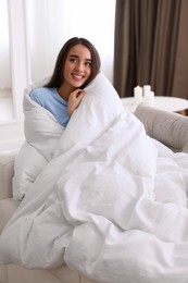 Woman covered in blanket resting on sofa