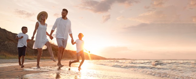 Image of Happy family running on sandy beach near sea at sunset, space for text. Banner design
