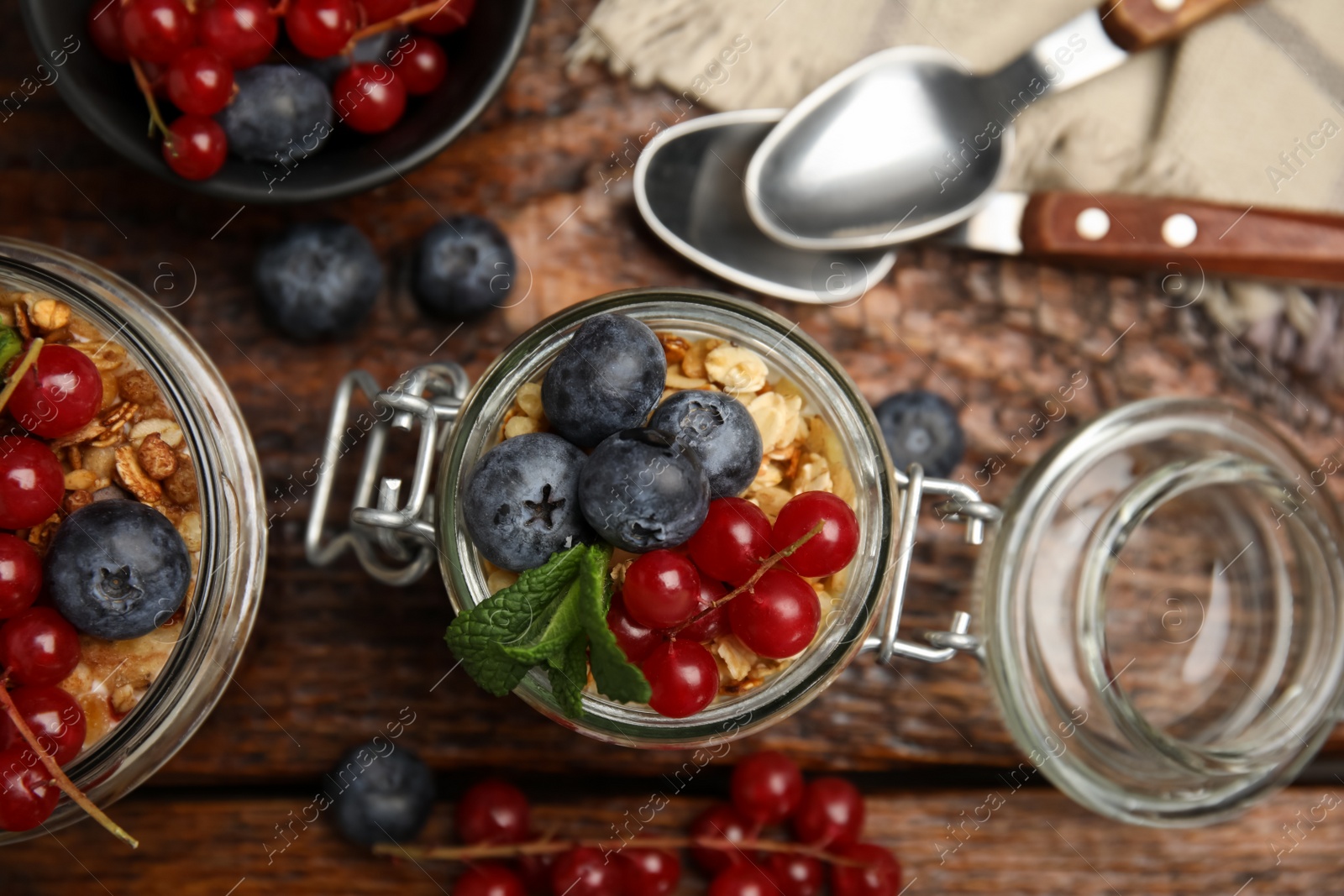 Photo of Delicious yogurt parfait with fresh berries and mint on wooden table, flat lay