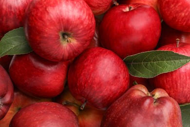 Photo of Fresh red apples and leaves as background, top view