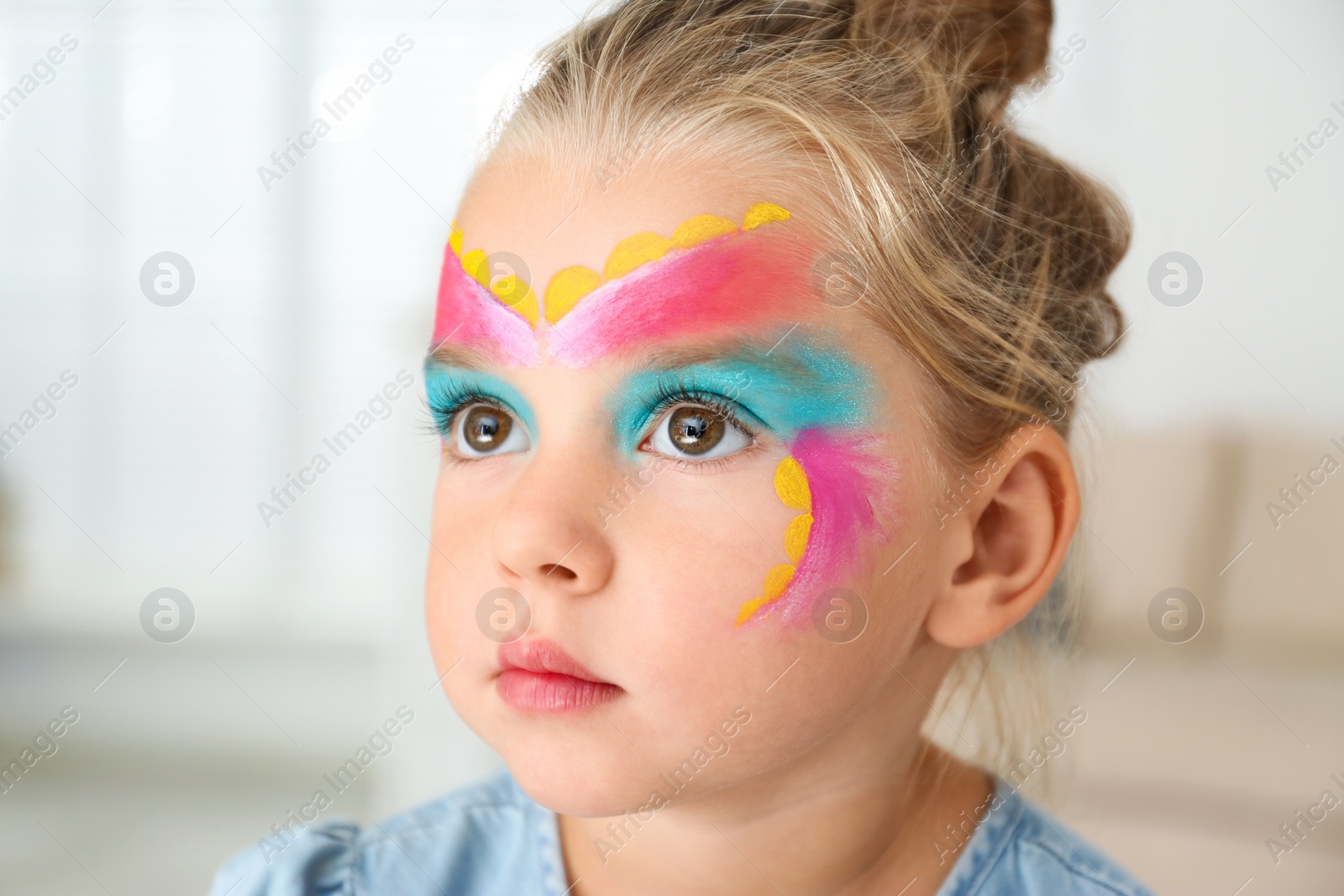 Photo of Cute little girl with face painting indoors