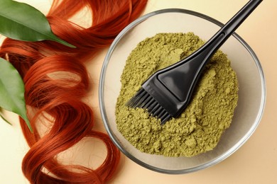 Photo of Bowl of henna powder, brush, green leaves and red strand on beige background, flat lay. Natural hair coloring