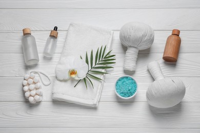 Photo of Beautiful spa composition with herbal massage bags and different care products on white wooden table, flat lay