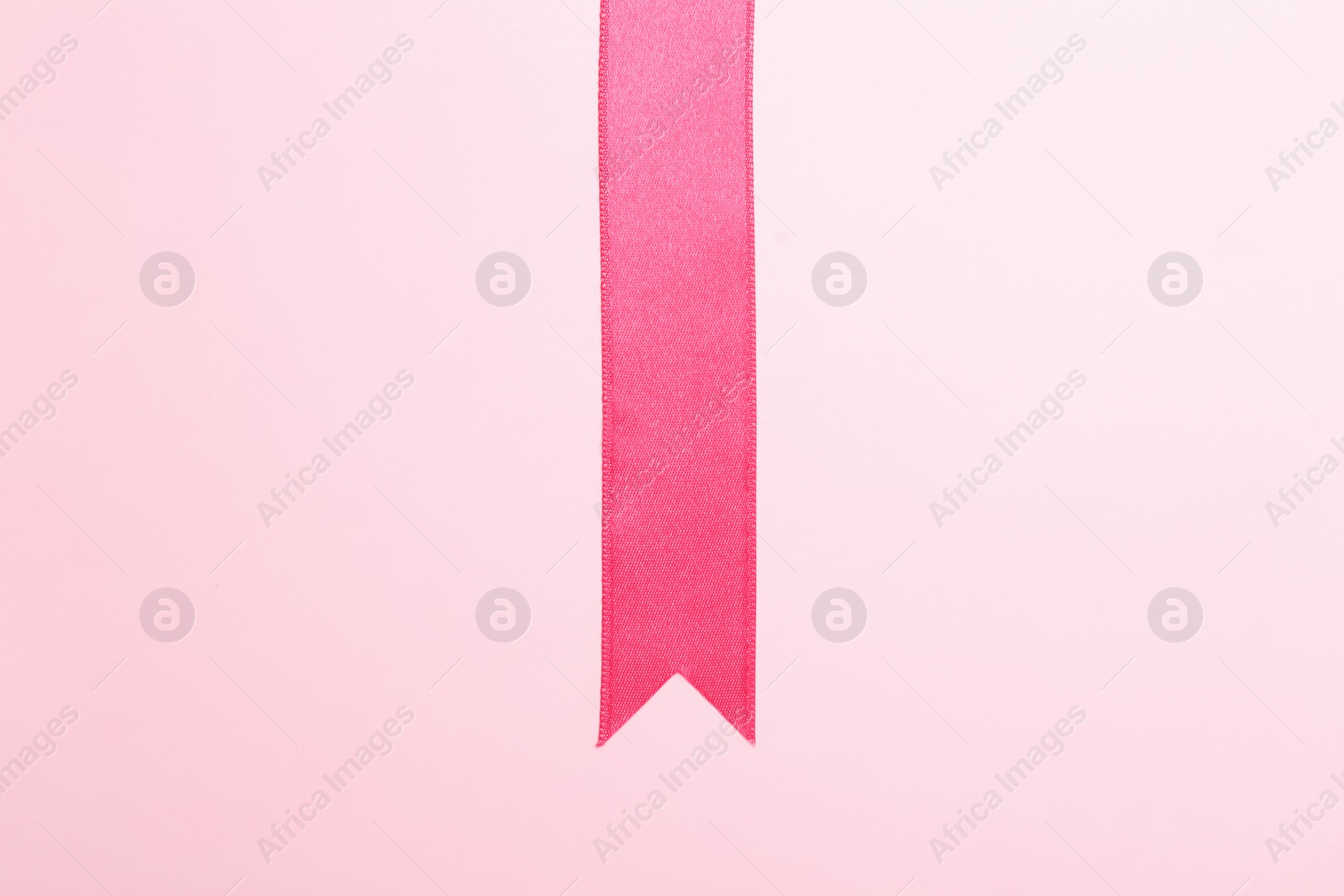 Photo of Simple pink ribbon on color background, top view