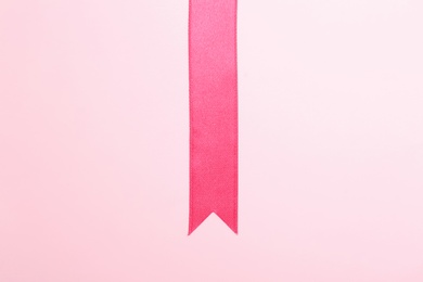 Photo of Simple pink ribbon on color background, top view