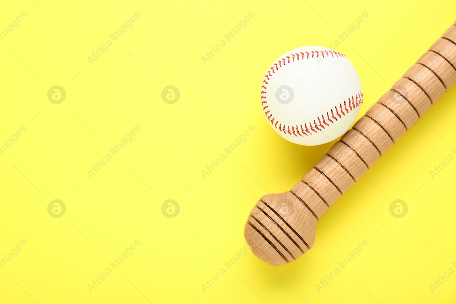 Photo of Wooden baseball bat and ball on yellow background, flat lay. Space for text