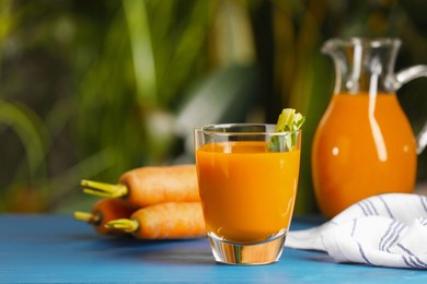 Tasty carrot juice on blue wooden table outdoors
