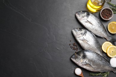Photo of Fresh dorado fish and ingredients on black slate background, flat lay. Space for text