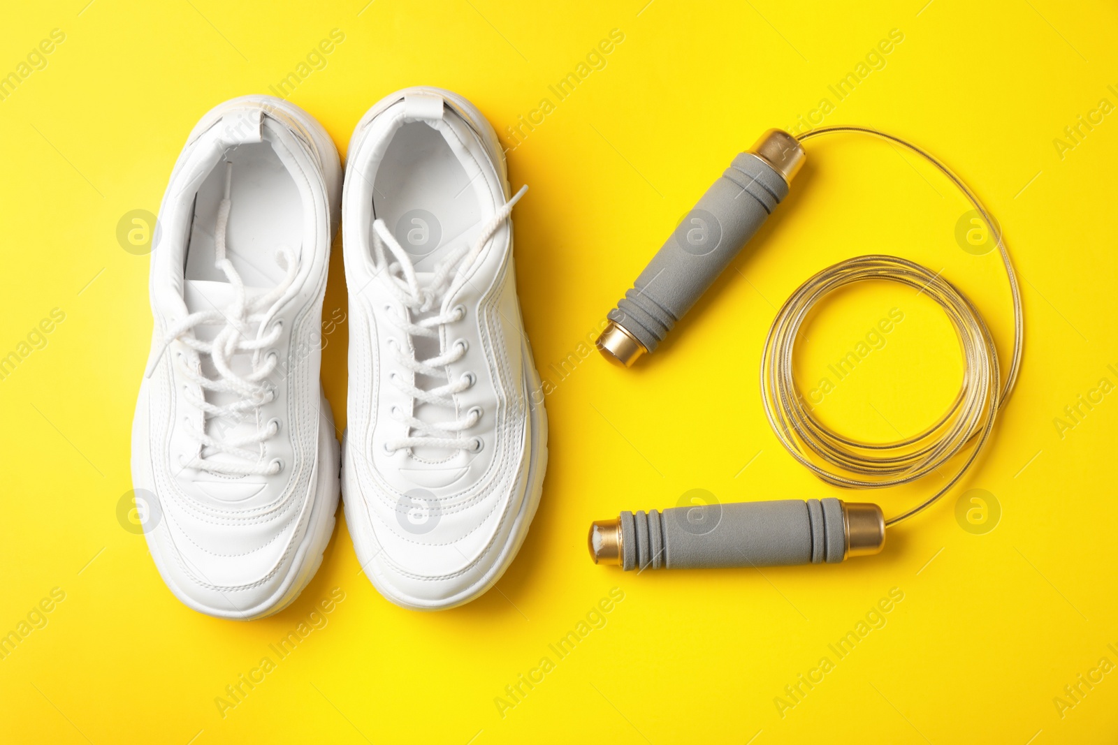 Photo of Jump rope and sneakers on color background. Healthy lifestyle