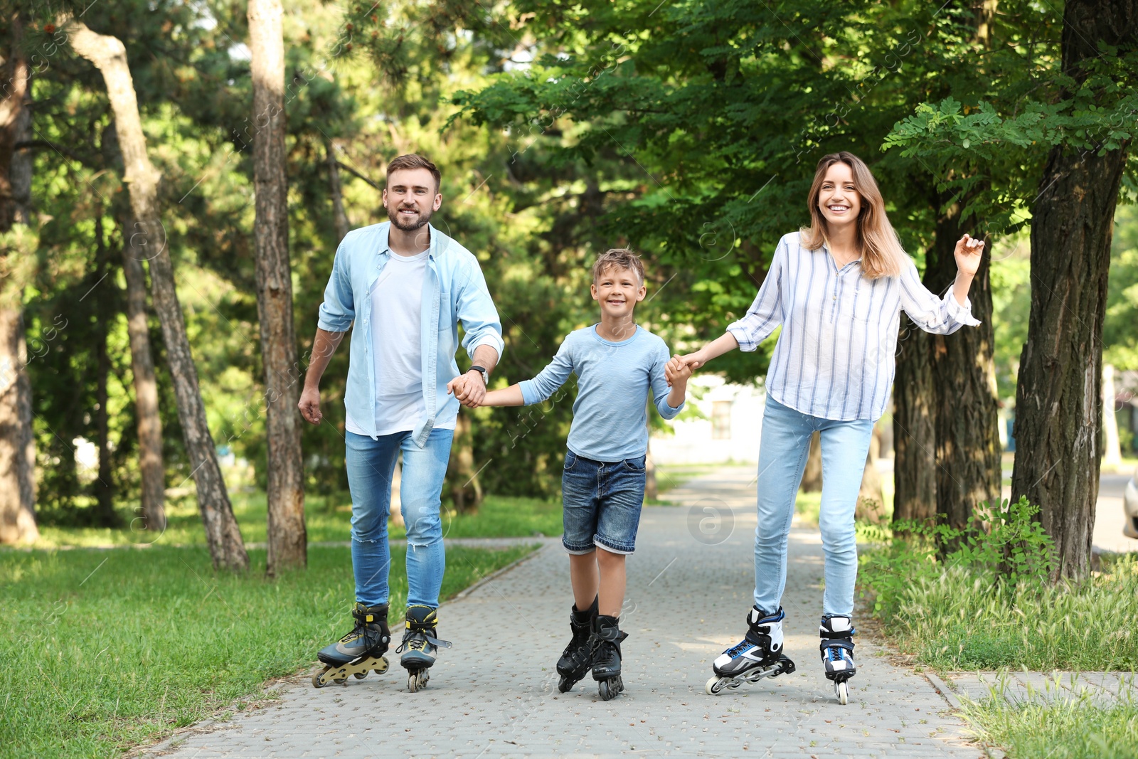 Photo of Young happy family roller skating in summer park